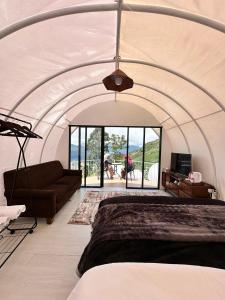 a bedroom with a large bed and a couch at Glamping Dieng Sunrise Point Larva Camp in Kejajar