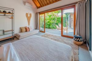 a bedroom with a bed and a large window at Villa Manouch in Nusa Lembongan