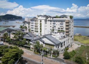 an aerial view of a white building next to the water at 夫婦露天風呂の宿吟松 in Ibusuki