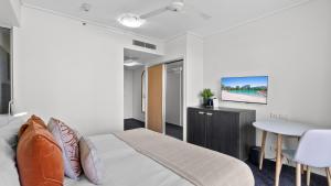 a bedroom with a bed and a table and a tv at Mantra Hotel Room in Cairns