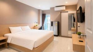 a bedroom with a white bed and a television at The Fifth Residence in Bangkok