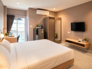 a bedroom with a large white bed and a tv at The Fifth Residence in Bangkok