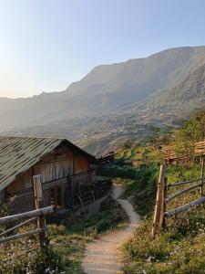 a barn and a dirt road next to a mountain at PhinFamilyHomestay in Tả Van