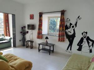 a living room with a mural of a woman playing a guitar at Ocean Shores Hospitality in Candolim