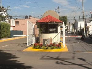 ein kleines Gebäude mit einem Tor und Blumen an einer Straße in der Unterkunft Casa Torremolinos en Coto Privado in Zapopan