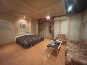 a bedroom with a bed and a couch and a table at Hotel Esta in Miyazaki