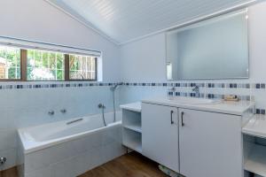 a white bathroom with a tub and a sink and a mirror at 3BR Lakeside Home Mountains Beach Nearby in Cape Town +21 photos
