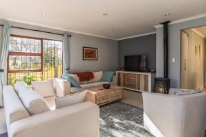 a living room with white couches and a tv at Peaceful Lakeside Retreat Near Muizenberg in Lakeside