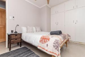 a white bedroom with a bed and a table at Peaceful Lakeside Retreat Near Muizenberg in Lakeside