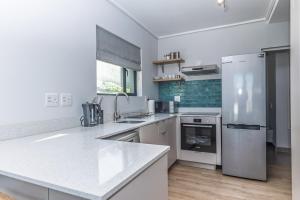 a kitchen with white counters and a refrigerator at Stylish Studio with Ocean Views at Wavescapes in Muizenberg