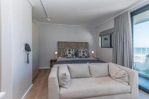 a living room with a couch in front of a bed at Stylish Studio with Ocean Views at Wavescapes in Muizenberg