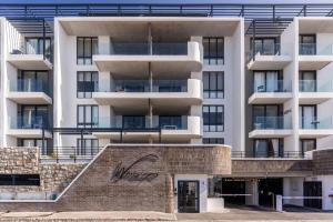 a large white building with a staircase in front of it at Stylish Studio with Ocean Views at Wavescapes in Muizenberg +5 photos
