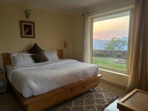 a bedroom with a bed and a large window at Highfield Villa in Kanatal