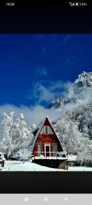 a red house in front of a snow covered mountain at Cottage Irko in Tvebishi