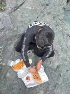 a man kneeling on the ground with a pair of bagels at Jungle Bungalow in Pahalgām