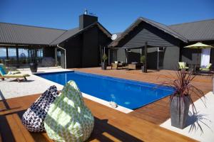 a house with a swimming pool with vases on a deck at Lodore Lodge in Kerikeri