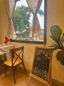a table and a chair and a sign in front of a window at Homestay Mẹ Mít in Cu Chi