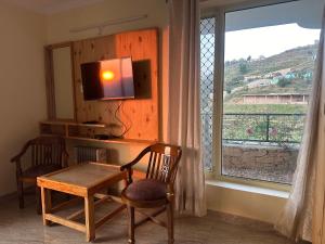 a room with a table and chairs and a window at Highfield Villa in Kanatal