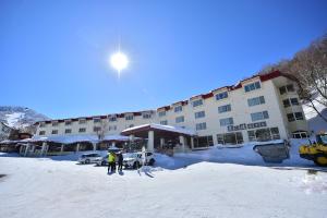 two people standing in front of a building in the snow at Kumanoyu Hotel in Yamanouchi