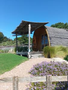 a small house with a garden with purple flowers at Su Niberalzu glamping in Fermata di Enas