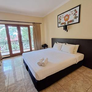 a bedroom with a bed with two white towels on it at Grand Pujon View in Songgoriti