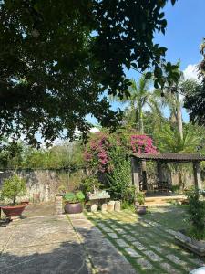a garden with a bench and pink flowers and trees at Homestay Mẹ Mít in Cu Chi