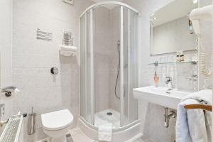 a bathroom with a shower and a toilet and a sink at Hotel Trinity in Olomouc