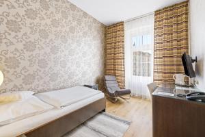 a bedroom with a bed and a desk and a television at Hotel Trinity in Olomouc