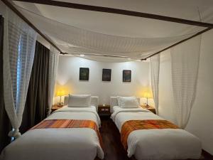 two beds in a room with white walls and windows at Mango Tree Resort in Chiang Mai