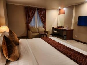a hotel room with a large bed and a desk at Olympic Hotel Jakarta in Jakarta +27 photos