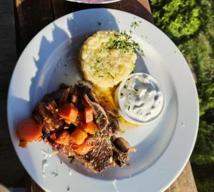 a plate of food with meat and vegetables and mashed potatoes at Pensiunea Lostrita in Buhalniţa