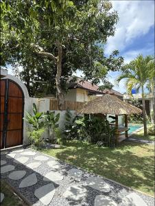 a garden with a fence and a table and a tree at Nira Hostel Kuta Lombok in Kuta Lombok