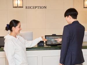 a woman standing next to a cash register with a man at THE DAY HOTEL ShinYokohama in Yokohama