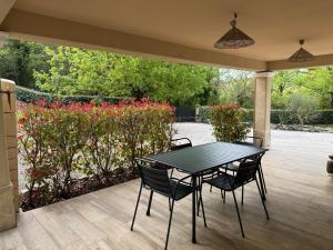 a black table and chairs on a patio with flowers at Chez Christine in Callian