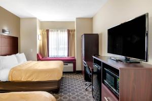 a hotel room with a bed and a flat screen tv at Quality Inn Overland Park Kansas City in Overland Park