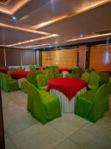 a room with green chairs and tables and red and green tables at Hotel Roselle inn in Jāmb