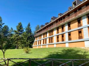 a building with a green field next to a fence at Pescasseroli Home in Pescasseroli