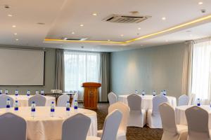 a conference room with white tables and chairs and a screen at Giraffe Beach Hotel in Dar es Salaam