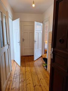 an empty hallway with two white doors and a wooden floor at Helles geteiltes Mehrbettzimmer in Leipzig