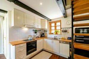 a kitchen with white cabinets and a black appliance at Romantic Nights Under The Thatched Roof in Scharnebeck