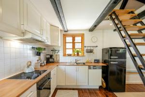 a kitchen with white cabinets and a black refrigerator at Romantic Nights Under The Thatched Roof in Scharnebeck