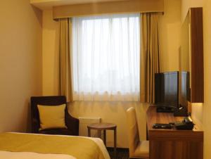 熊谷市にあるホテルサンルート熊谷駅前のベッドとテレビが備わるホテルルームです。
