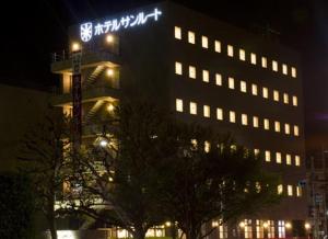 a large building with a sign on it at night at Hotel Sunroute Kumagaya Station in Kumagaya