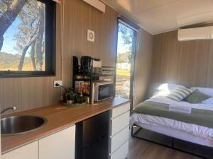 a kitchen with a sink and a bed in a tiny house at Tallarook Hilltop Tiny House 2 by Tiny Away in Tallarook
