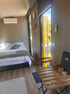 a bedroom with a bed and a bench next to a door at Tallarook Hilltop Tiny House 2 by Tiny Away in Tallarook