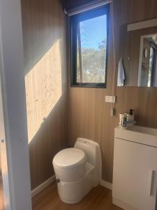 a bathroom with a white toilet and a window at Tallarook Hilltop Tiny House 2 by Tiny Away in Tallarook