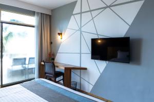 a bedroom with a desk and a tv on a wall at Giraffe Beach Hotel in Dar es Salaam