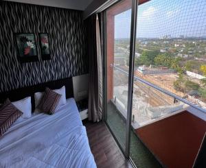 a bedroom with a bed and a large window at Weekend address in Surat
