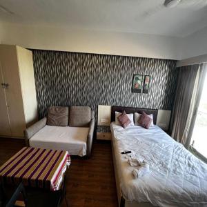 a hotel room with two beds and a couch at Weekend address in Surat