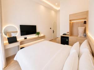 a bedroom with a white bed and a flat screen tv at Amory Airport Hotel in Ho Chi Minh City